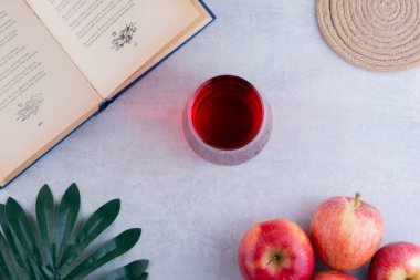 Kitap, bir bardak meyve suyu ve arkaplanda elmalar, üst manzara.