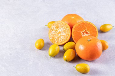 Gri bir zemin üzerinde taze kumkatlar ve mandalinalar. 