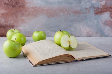 Mutfak masasında taze elmalar ve kitap. Metin için boş alan. 