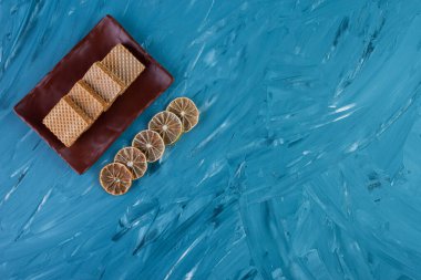 Waffle ve limon dilimlerinin mavi arka planda üst görüntüsü.