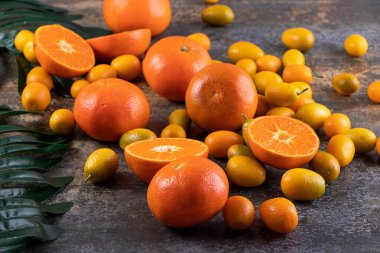 Gri bir zemin üzerinde taze kumkatlar ve mandalinalar. 