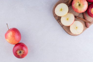 Tahtada olgun elma ve tarçın çubukları var.