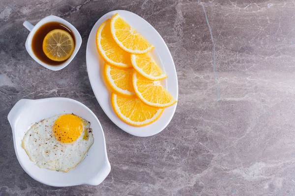 breakfast with egg, tea and orange on a white background. top view.