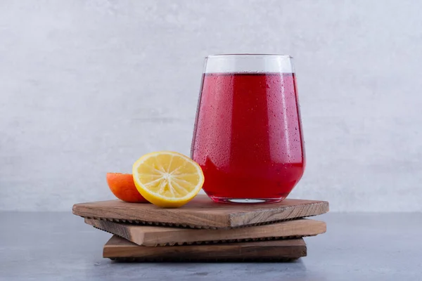 glass of red juice with fresh fruits on wooden boards