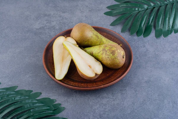 Olgun yeşil armutlar gri bir zemin üzerinde kil plaka. 