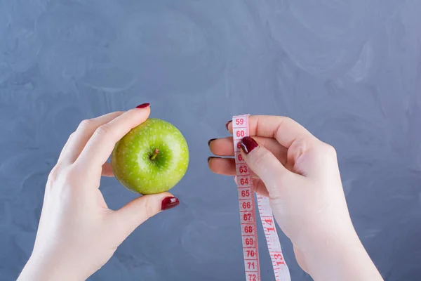 woman holding apple and measuring tape. diet concept.