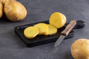 Gri arka planda bıçakla haşlanmış patatesler.