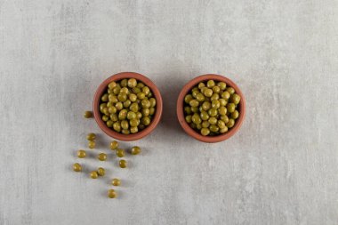 Arka planda gri bir çanakta yeşil bezelyeler. en üstteki görünüm.