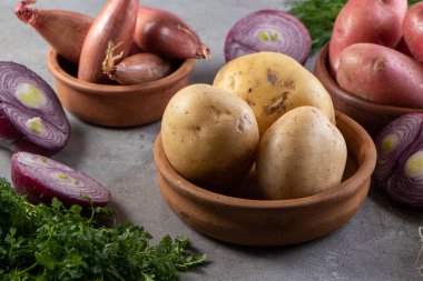 Tahta arka planda kilden bir tencerede taze organik patatesler.