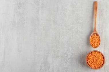 Gri arka planda tahta kaşıkta kırmızı mercimek