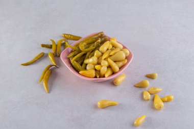 Taş masada pembe bir kase kırmızı biber turşusu. Yüksek kalite fotoğraf