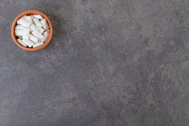 Taş zemine yerleştirilmiş beyaz sakızlarla dolu bir kase. Yüksek kalite fotoğraf