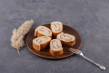 Tahta tabakta, arka planda dilimlenmiş sünger rulo kek. Yüksek kalite fotoğraf