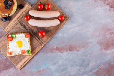 Tost ve kaynamış sosisle birlikte taş masaya konmuş leziz gözlemeler. Yüksek kalite fotoğraf