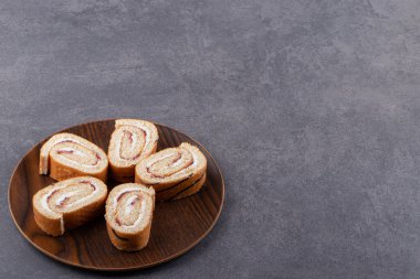 Tahta tabakta, arka planda dilimlenmiş sünger rulo kek. Yüksek kalite fotoğraf