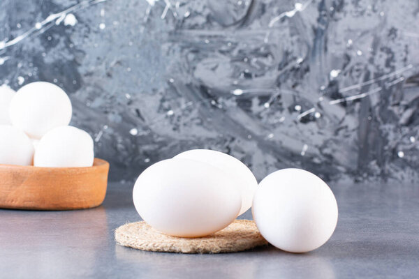 Fresh raw white chicken eggs placed on beige table . High quality photo