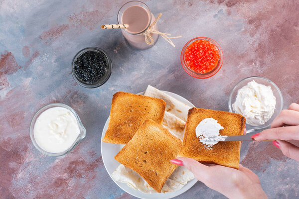 Female hands spreading cream on toast on marble background. High quality photo