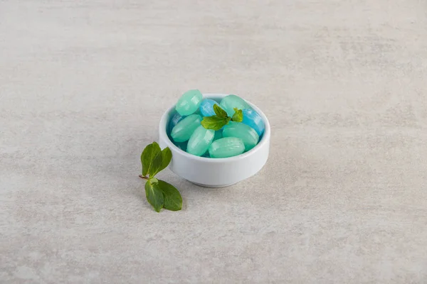 Blue and green hard candies in bowl placed on stone table. High quality photo