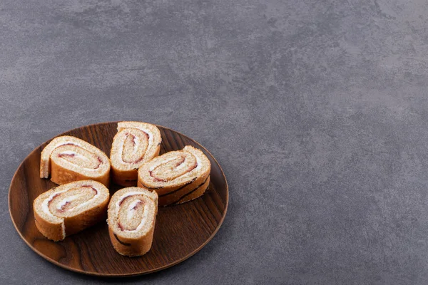 Tahta tabakta, arka planda dilimlenmiş sünger rulo kek. Yüksek kalite fotoğraf