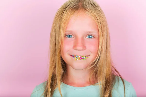 A kislány élvezi az édességet. A lány sokszínű cukorral az ajkain. Cukorfüggőség gyermekeknél — Stock Fotó