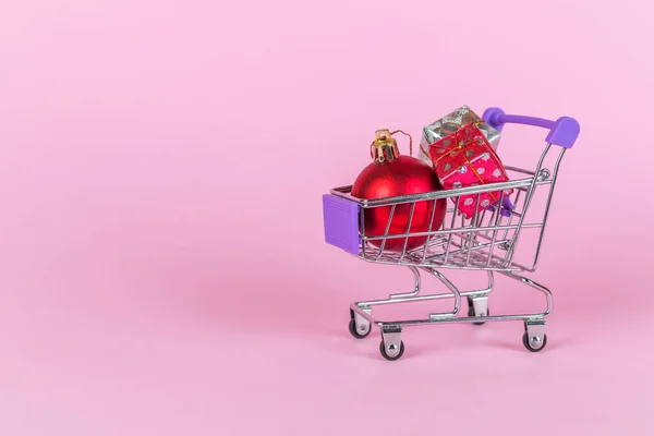 Palline di Natale e scatole regalo nel carrello della spesa. Idea di shopping natalizio. Saldi vacanze invernali, vendita on-line. — Foto Stock