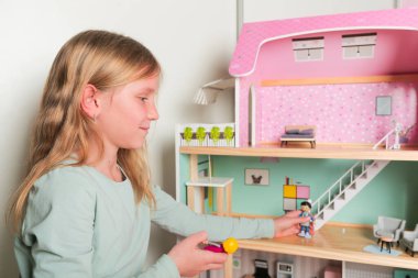 Mutlu kız oyuncak bebek evi ve bebeklerle oynuyor. Mutlu çocuk.