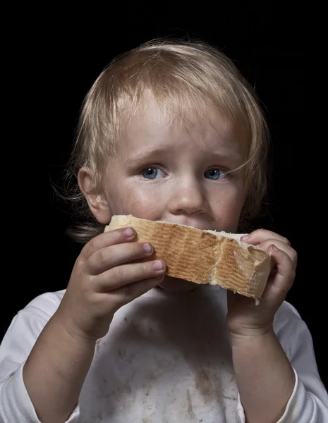 Criança faminta comer pão — Fotografia de Stock