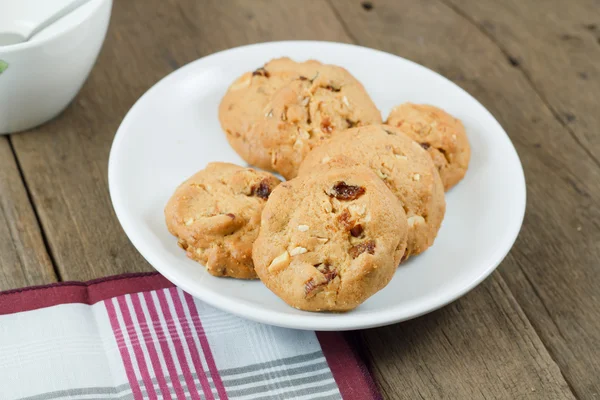 Çikolatalı kurabiye beyaz disk üzerinde ahşap masa