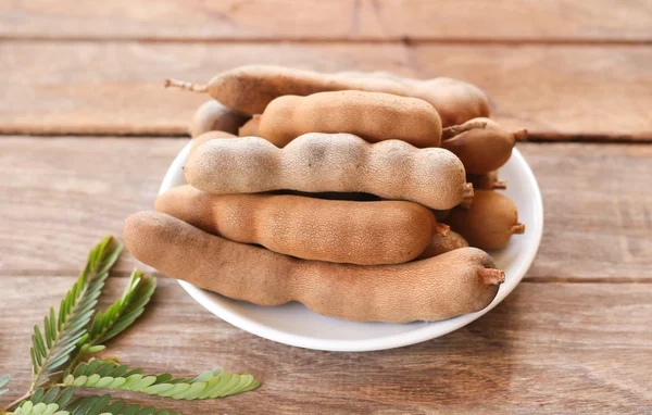 Close up ripen sweet tamarinds in white disk put on wooden table — Stock Photo, Image