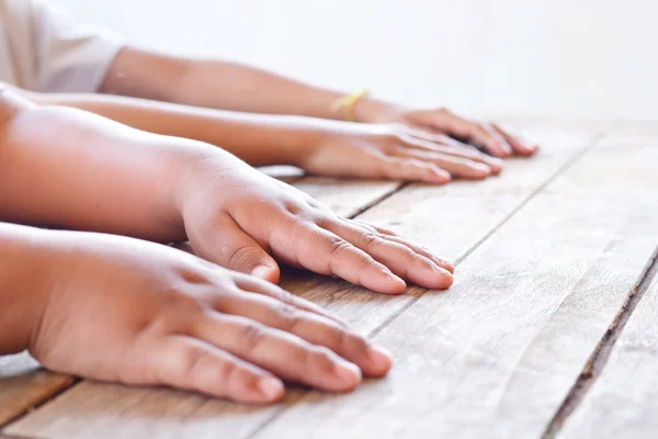 Los niños ponen sus manos en la mesa de madera, centrado en la mano izquierda de f — Foto de Stock