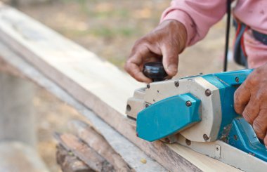 Bir tahta uçak için adam elektrikli bir kazıyıcı ayarlama.