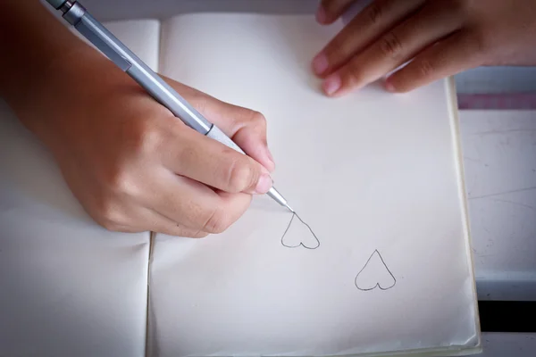 Діти малюють форму серця на своїй записниці . — стокове фото
