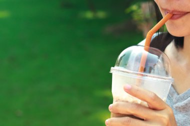 Asyalı kadınlar plastik bardakta süt ile buzlu kahve içme.