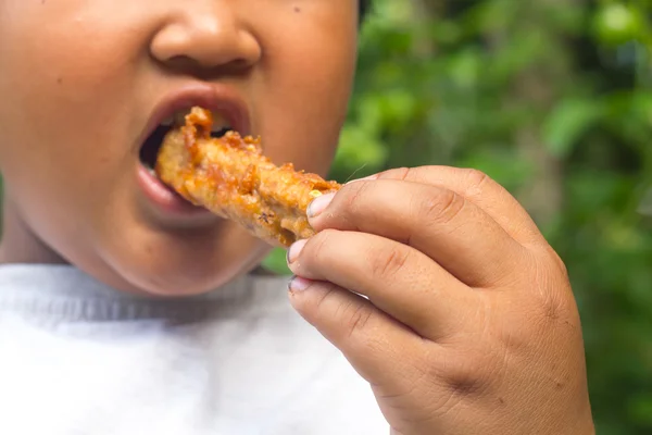 Egy ázsiai fiú eszik sült banán, hogy Thaiföld tipikus snack. — Stock Fotó