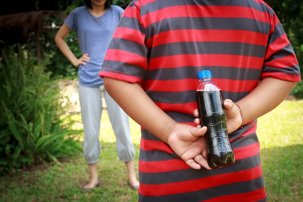 The boy hid a bottle of cola On his back. — Stock Photo, Image