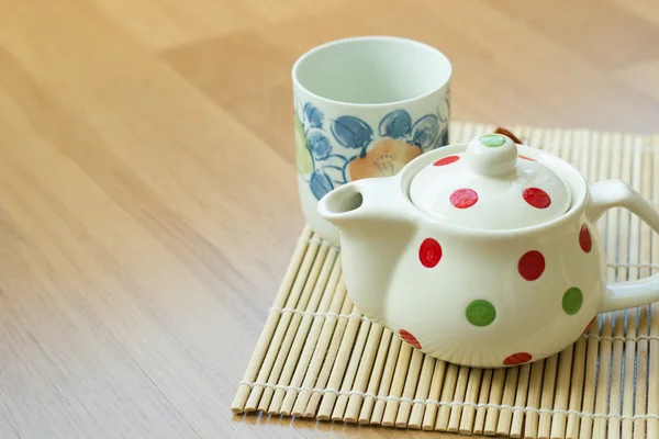 Tea pot and cup on wooden table. Stock Photo