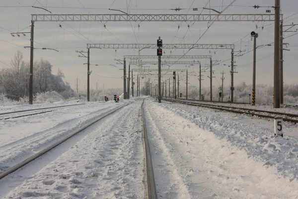 Vías férreas electrificadas con señales rojas - estación ferroviaria con señal de tráfico en invierno — Foto de Stock