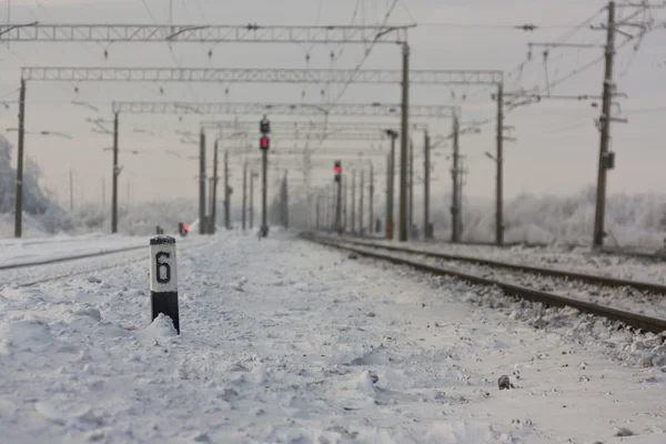 Vías férreas electrificadas con señales rojas - estación ferroviaria con señal de tráfico en invierno — Foto de Stock