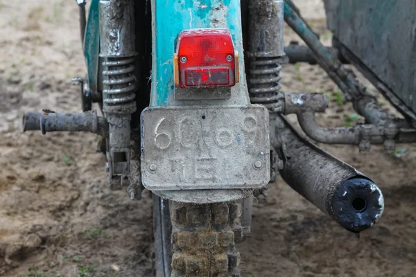 An old motorcycle - partial view of  back part with taillight,  wheel and  muffler on the off road, tricycle — Stock Photo, Image