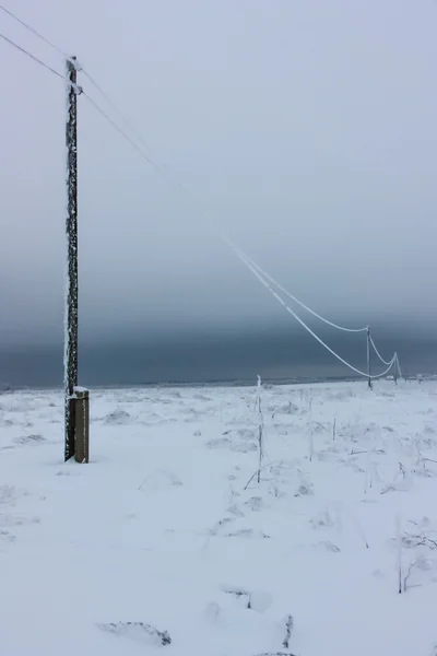 Líneas eléctricas de fase rota con escarcha en los postes eléctricos de madera en el campo en el invierno después de la tormenta — Foto de Stock