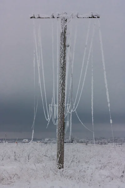 Прорванная фаза электрических линий с инеем на деревянных электрических столбах в сельской местности зимой после шторма — стоковое фото