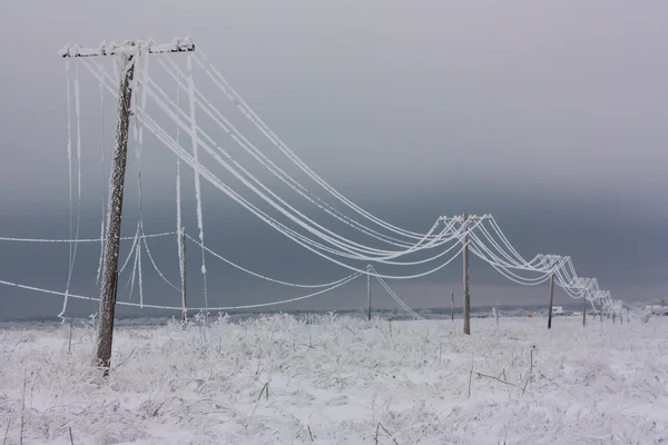 Líneas eléctricas de fase rota con escarcha en los postes eléctricos de madera en el campo en el invierno después de la tormenta — Foto de Stock