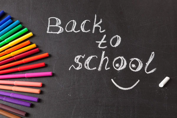 Powrót do szkoły tło z kolorowymi mazakami i tytuł "Powrót do szkoły" napisany przez białą kredą na tablicy szkoły — Zdjęcie stockowe