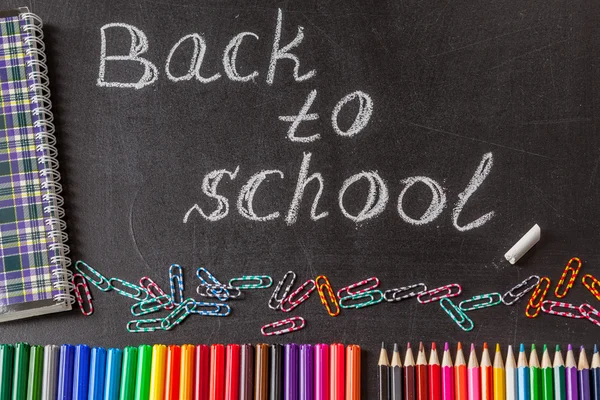 Back to school background with colorful felt tip pens, pencils, clips, notebook and the title "Back to school" written by white chalk on the  chalkboard — Stock Photo, Image