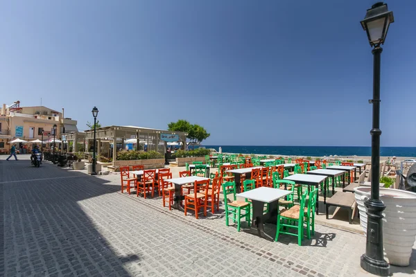 Rethymnon, ön Kreta, Grekland, - 1 juli 2016: syn på kaféet med färg stolar som ligger nära banvallen av Medelhavet — Stockfoto