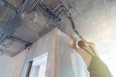 İşçi, binanın iç elektrik tesisatının bir parçası olan elektrik kablolarını inşaat, tadilat, yenileme, uzatma, restorasyon ve yeniden inşa aşamasında olan tavana yerleştiriyor.