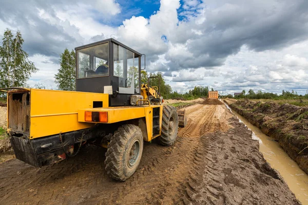 Yol inşaatı ve inşaat makinelerinden biri - buldozer asfaltlamadan önce yoldaki kumu dümdüz ediyor.