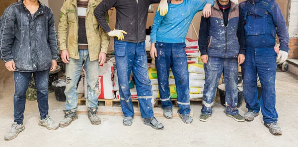 Werknemers en bouwers en voorman zijn als bende met vuil uniform verblijven in appartement dat in aanbouw is, verbouwing, renovatie, uitbreiding, restauratie, revisie en wederopbouw Rechtenvrije Stockfoto's