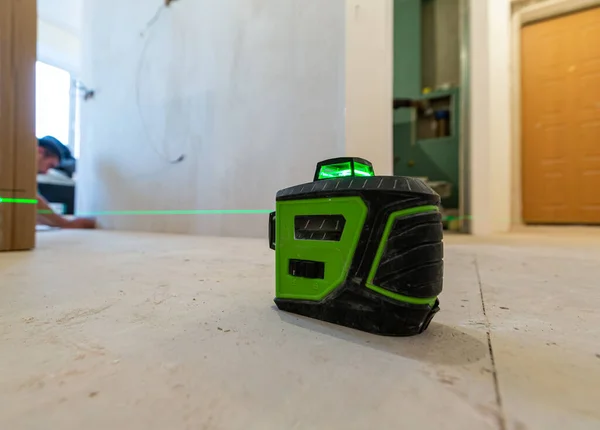 Bouwer werkt met een laser constructie niveau in het appartement dat in aanbouw is, verbouwing, renovatie, revisie, uitbreiding, restauratie en wederopbouw. Begrip "verbetering van de woning" Stockfoto