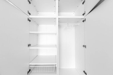 Yeni boş gardırop rafları beyaz ahşap kaplamalı ve kapıları açtı. Askılı dolap ve beyaz yatak odasındaki demiryolu rafı..